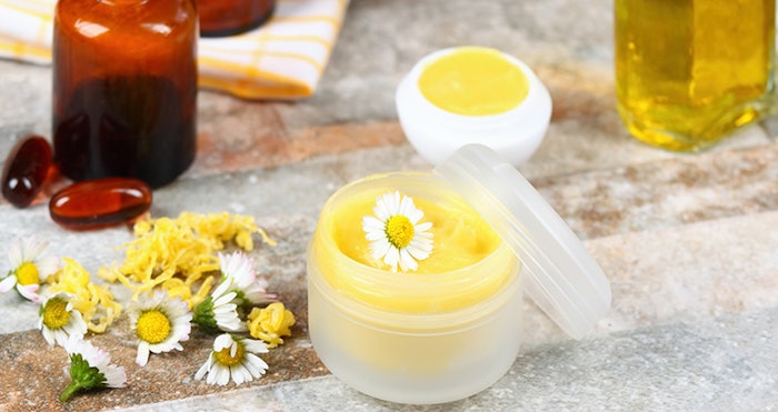 Homemade balm on lips decorated with daisy flowers