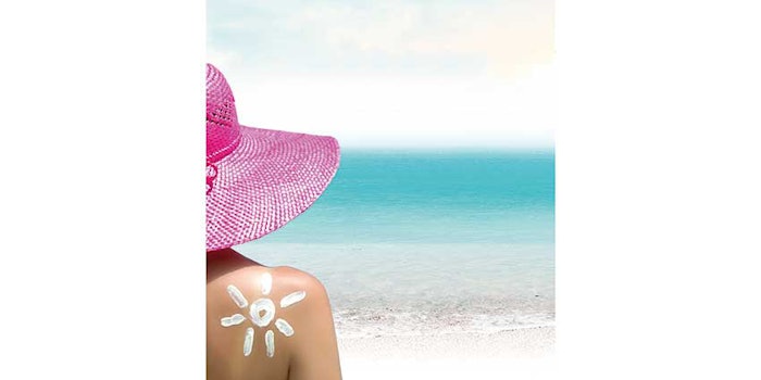 Woman in sun hat wearing sunscreen in shape of sun