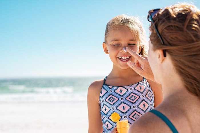 Young mother applying sunscreen on daughter nose at the beach by iStock/Ridofranz