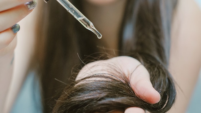Girl applying oil to hair