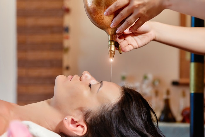 woman receiving Ayurveda Shirodhara spa treatment