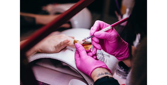 Manicurist works on subject's nails.