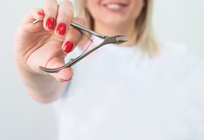 Hand holding cuticle nippers.