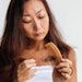 Woman looks at comb with a hair clump inside the bristles.