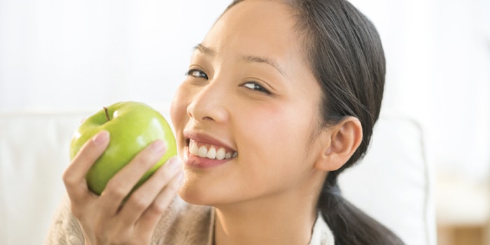 An individual snacks on a green apple.