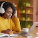 Smiling black girl with headset studying online, using laptop