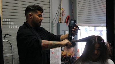 Cosmo Prof Artistic Team Member Jon Carlos De La Cruz completes his signature blowout on his model at the World of Texture set in Dallas, Texas.