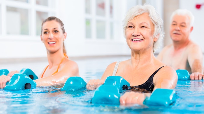 People young and senior in water gymnastics physiotherapy with dumbbells