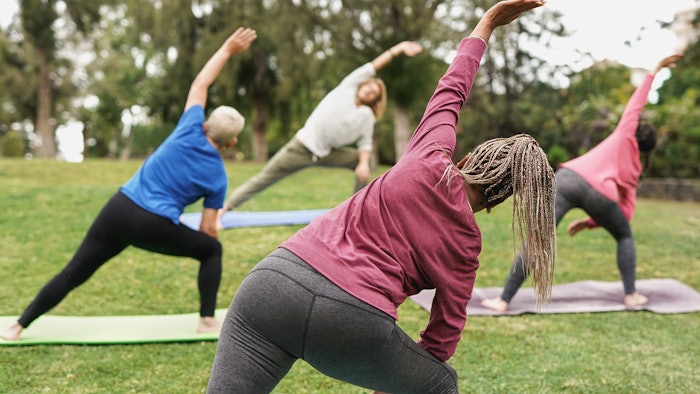 Multiracial people doing yoga class outside