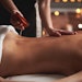 massage therapist pouring therapeutic oil onto client back for pain relief treatment