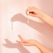 Woman dripping skin care serum into hand