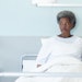 African american senior female patient lying in bed in sunny hospital room
