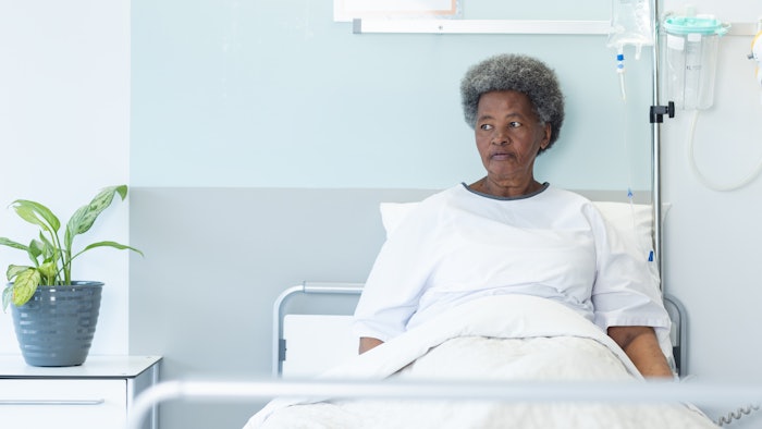 African american senior female patient lying in bed in sunny hospital room