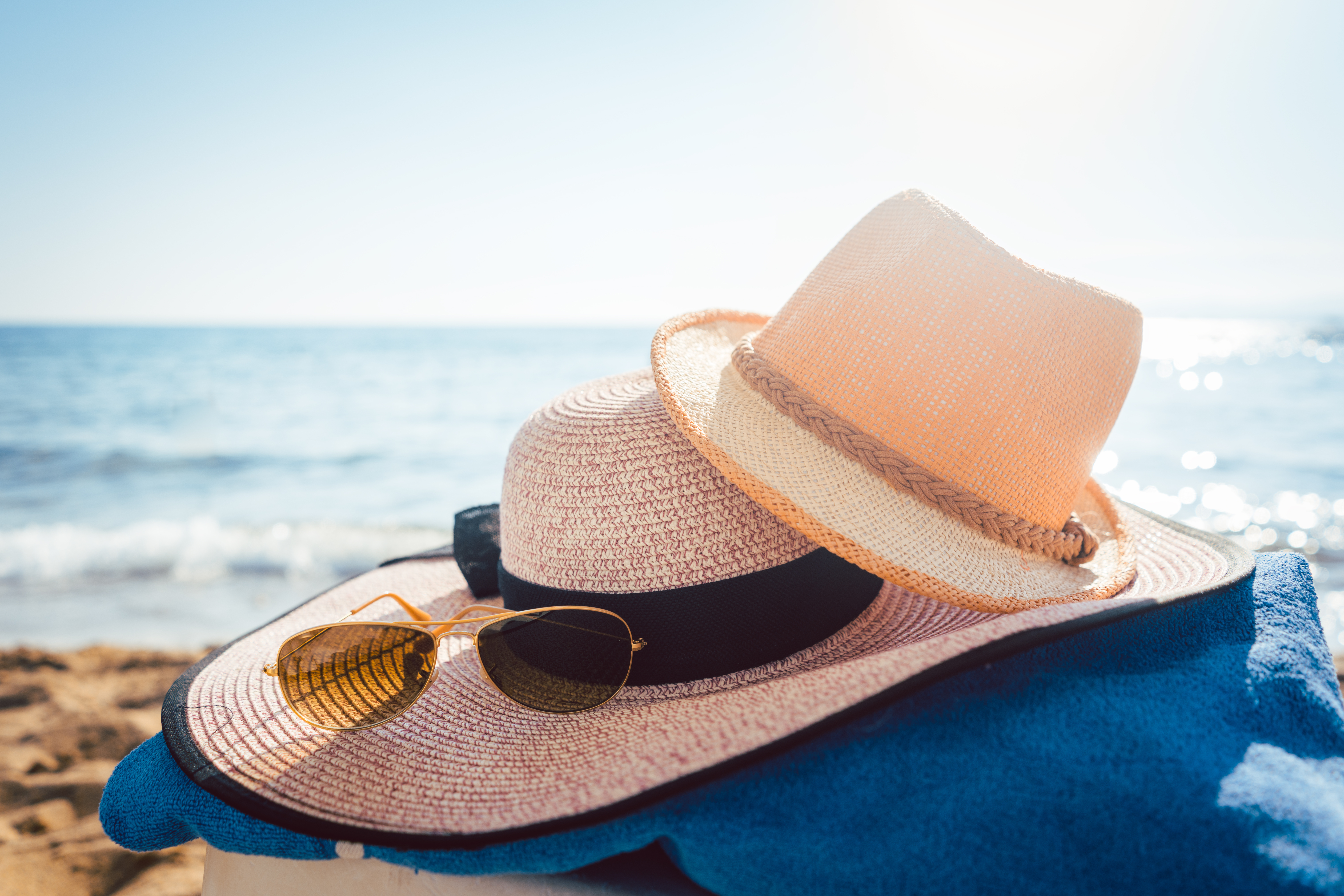 Sun hats and glasses on beach in the sand by the water