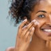 Woman applying moisturizer on face