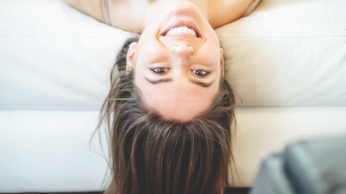 Woman Hanging Upside Down On Couch Smiling