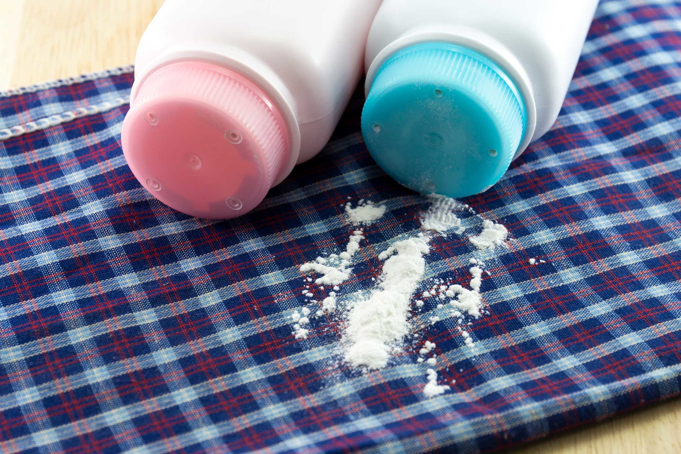 pink blue baby powder bottles spilled on plaid blanket