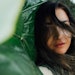 woman outside standing near large leaves wind blowing, beach and jungle background