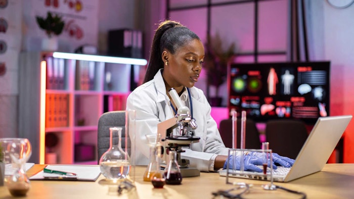 black female chemist running tests in lab computer glassware samples AdobeStock_520884932