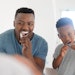 black man adult and child brushing teeth in mirror
