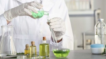 chemist at lab bench pouring liquid in glassware mixing science concept