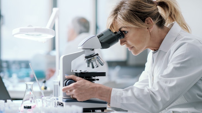 female caucasian chemist studing samples in lab under microscope