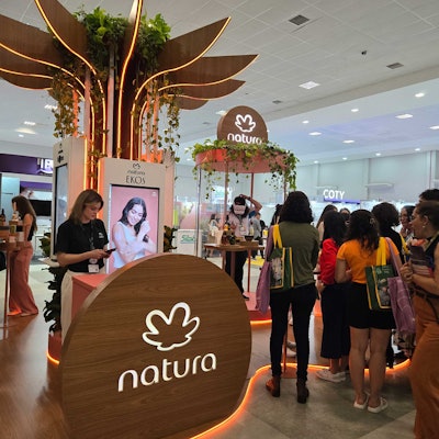 Attendees engage in fragrance and product samples by Natura, including entering a VR sensory booth for an interactive experience.