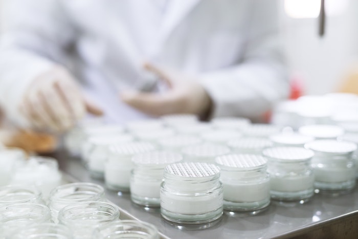 Close up picture of packing a face cream in glass jars.