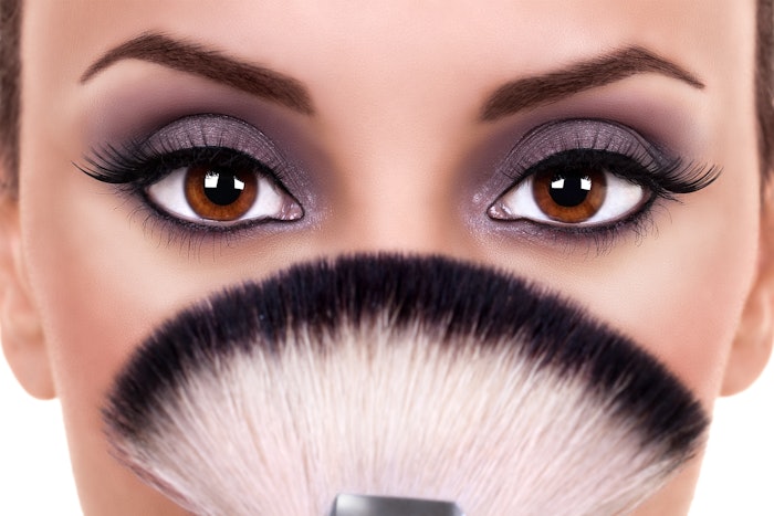 Woman with a smoky eye behind a makeup brush