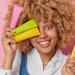 black woman holding toothbrushes toothpaste smiling bright colors
