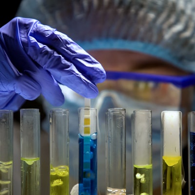 chemist in lab taking pH readings from test tubes