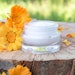 Calendula skin care outside flowers and cream in jar on stump