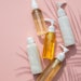 palm shadow bottles of skin care laying on pink background