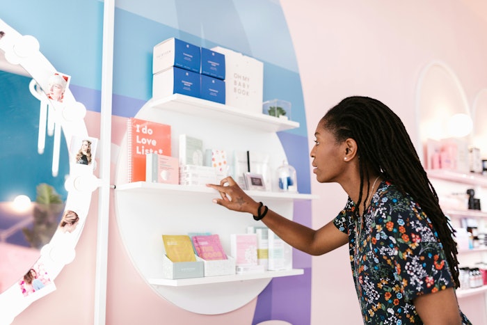 A woman in a floral shirt looking at products on a shelf.