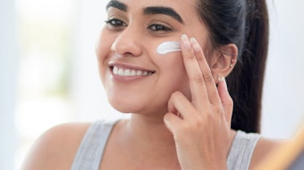 young beautiful woman smiling in mirror using product