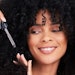 black woman curly hair using serum smiling