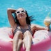 woman in pool floating pink tube sunglasses tropical drink