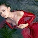 woman in red dress floating in water with algae