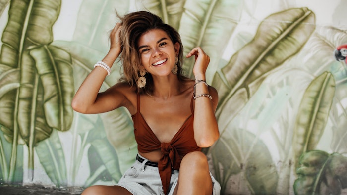 young woman playing with hair in front of rainforest backdrop
