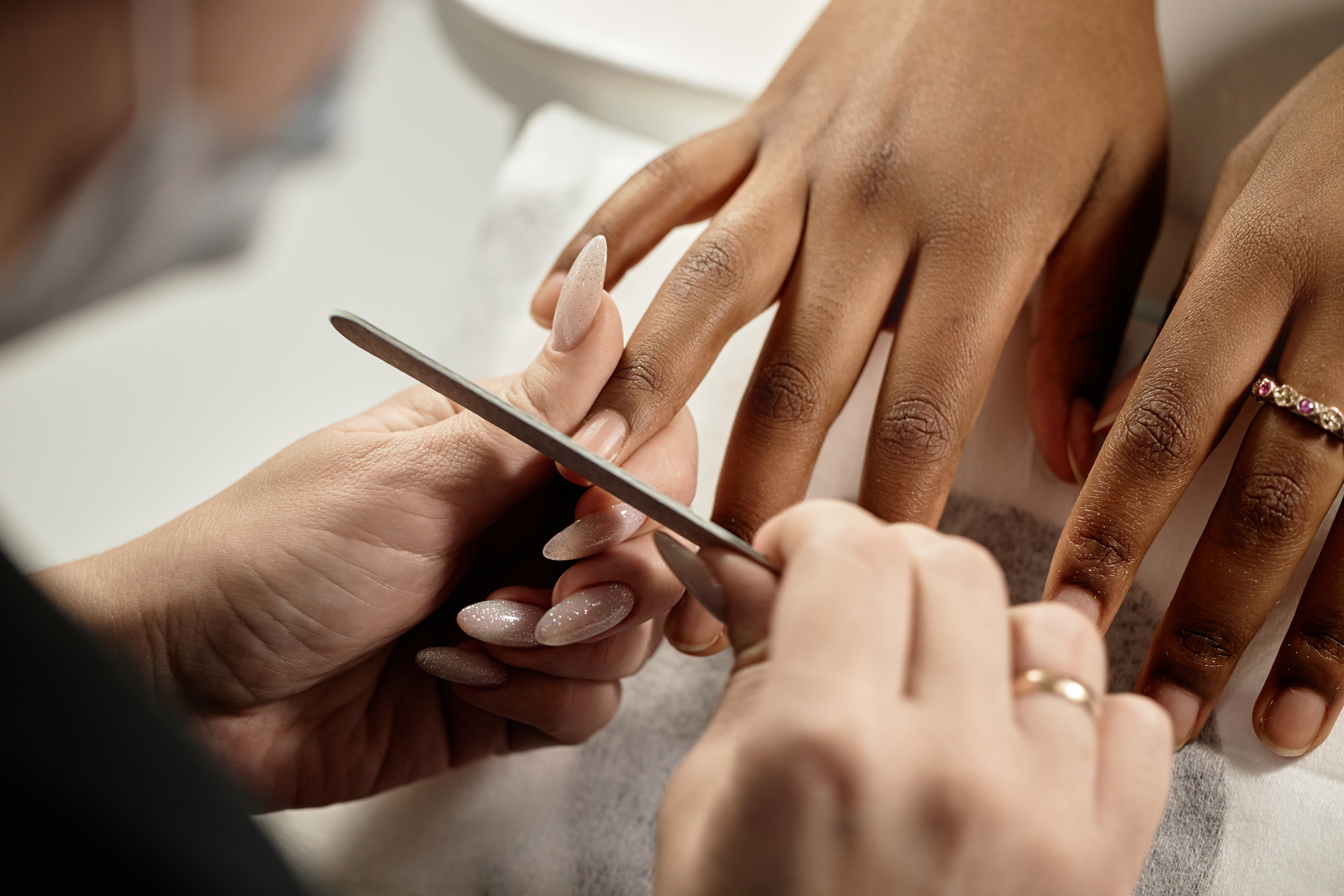 Nail tech files a client's nails in the salon.