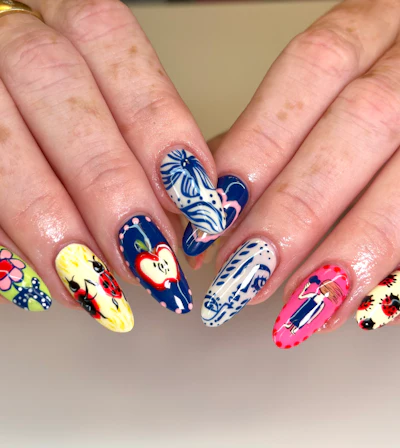 Abstract nail art that features lady bugs, apples, a person blowdrying their hair and more