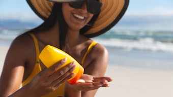 Woman On Beach With Floppy Sun Hat Applying Sunscreen Adobe Stock 426393637