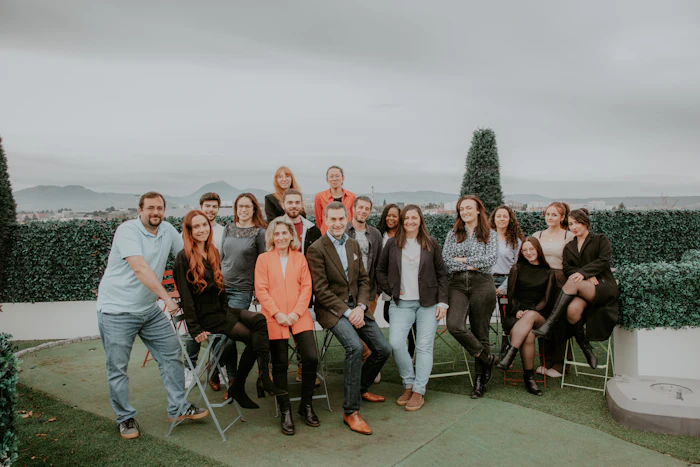 Team photo of diverse group on rooftop terrace with mountain landscape background