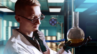 Chemist In Lab Looking At Liquid In Flask Thinking Adobe Stock 853750305