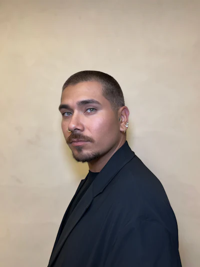 Professional portrait of a person in a black blazer against a neutral background