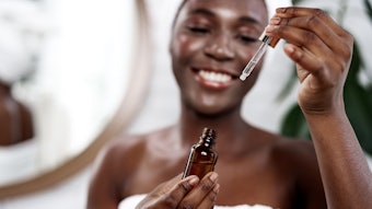 Beautiful Young Black Woman Towel Mirror Skin Serum Up Close Dropper Adobe Stock 1511571612
