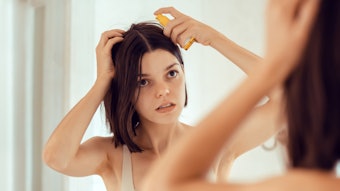 Woman Applying Gel Hair Serious Mirror Adobe Stock 877638796