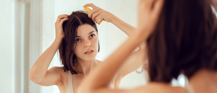 Woman Applying Gel Hair Serious Mirror Adobe Stock 877638796