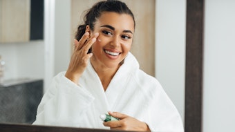 Young Beautiful Brunette Applying Eye Cream Looking Into Mirror Adobe Stock 400008735