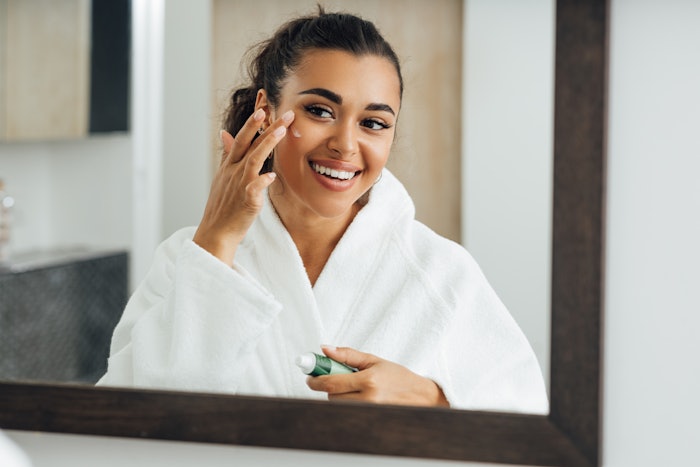 Young Beautiful Brunette Applying Eye Cream Looking Into Mirror Adobe Stock 400008735